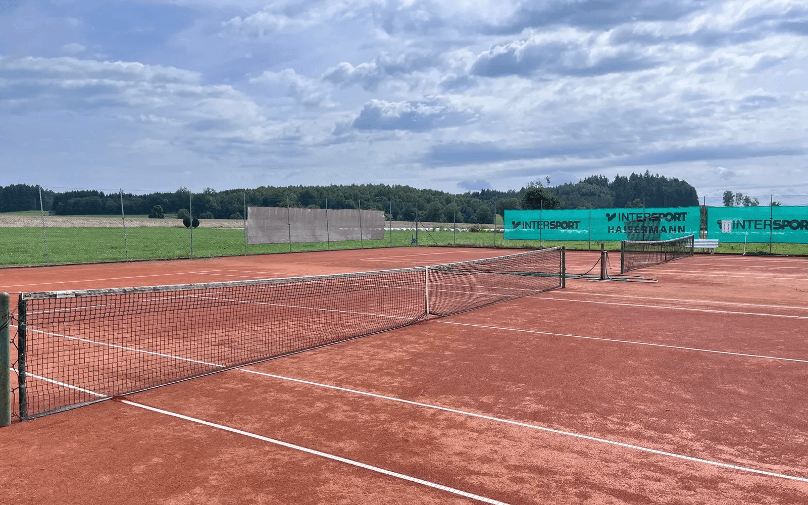 Tennissandplatz mit Netz und Windbanner