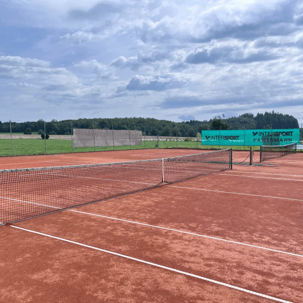 Hergerichteter Sandplatz mit Netz und Windbanner am Zaun